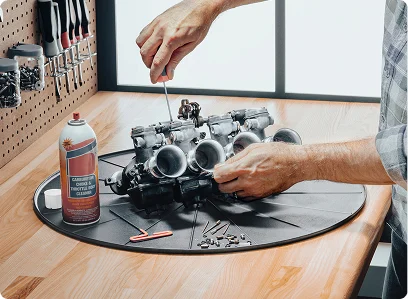 Man working on motor on top of round project mat